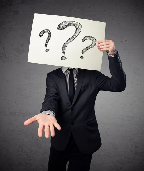 Businessman holding a paper with question marks in front of his — Stock Photo, Image