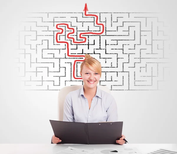 Business woman at desk with labyrinth and arrow — Stock Photo, Image