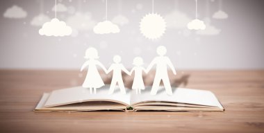 Ailenin karton figürleri açık bir kitabın üzerinde.