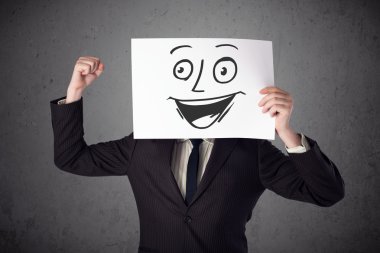 empresario sosteniendo una cartulina con cara sonriente en él en frente 
