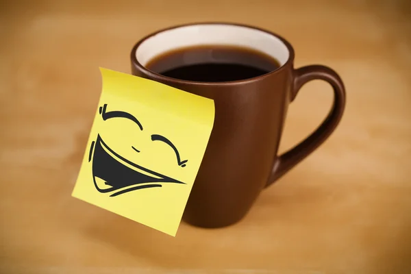 Post-it note with smiley face sticked on cup — Stock Photo, Image