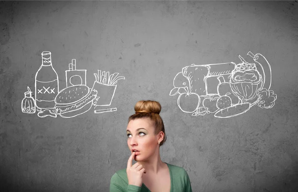 Woman standing between healthy and unhealthy foods — Stock Photo, Image