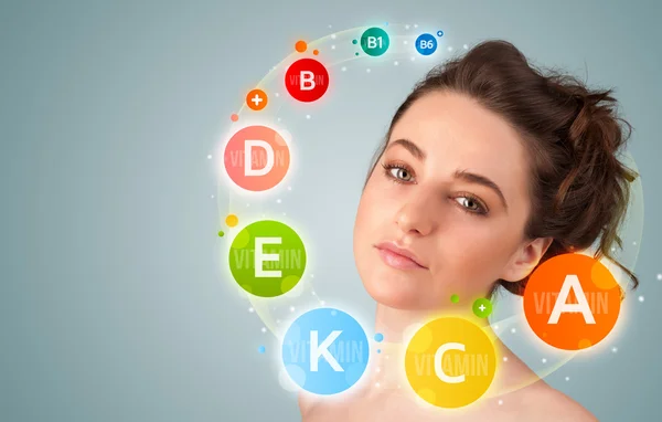 Pretty young girl with colorful vitamin icons and symbols — Stock Photo, Image