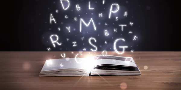 Open boek met gloeiende letters vliegen uit — Stockfoto