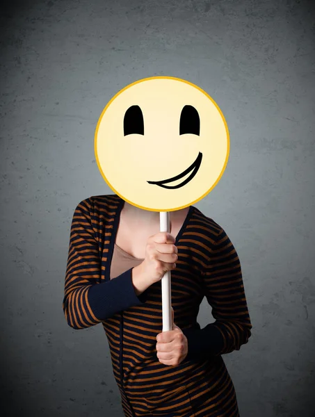 Giovane donna in possesso di un faccina faccina smiley — Foto Stock