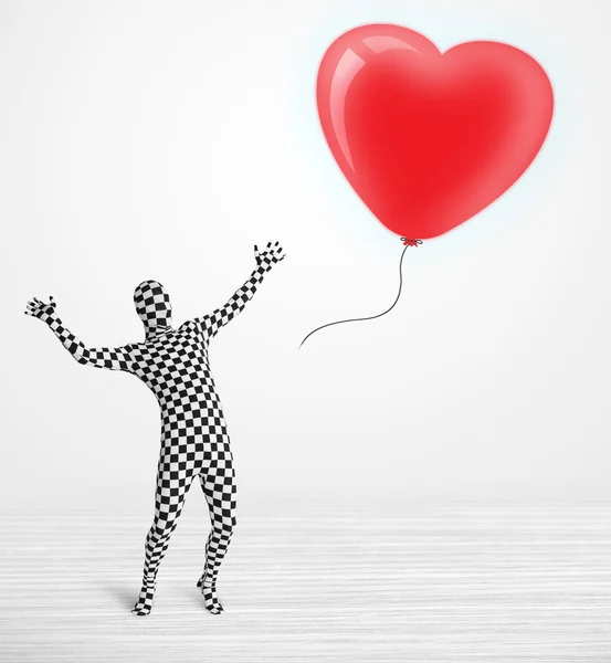 Cute guy in morpsuit body suit looking at a balloon shaped heart — Stock Photo, Image