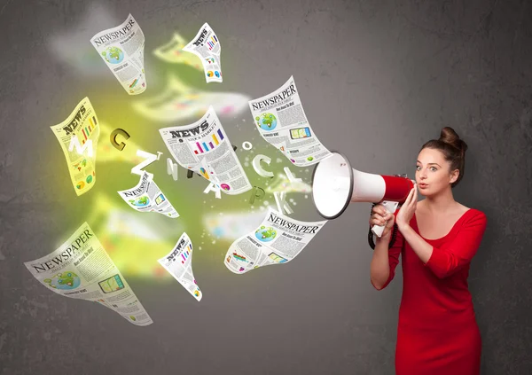 Girl yelling into loudspeaker and newspapers fly out — Stock Photo, Image