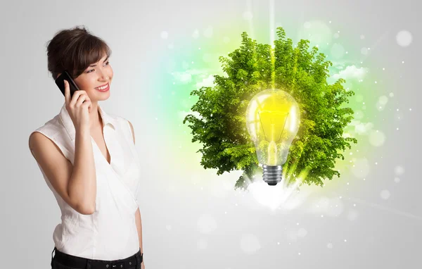 Jong meisje presenteren idee gloeilamp met groene boom — Stockfoto