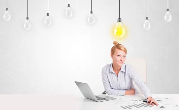 Business woman sitting at table with idea light bulbs — Stock Photo, Image