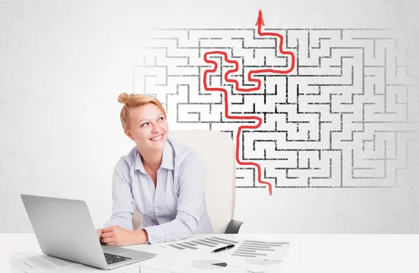 Business woman at desk with labyrinth and arrow — Stock Photo, Image