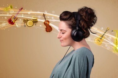 Kulaklıklı genç bir kadın müzik dinliyor.