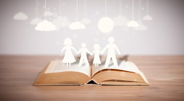 Ailenin karton figürleri açık bir kitabın üzerinde.