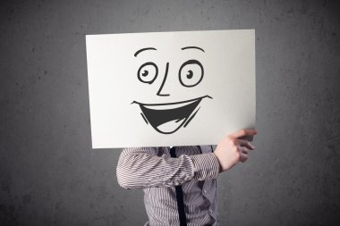 empresario sosteniendo una cartulina con cara sonriente en él en frente 