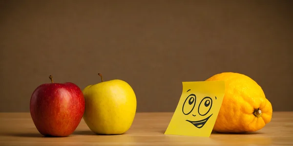 Lemon with post-it note looking at apples — Stock Photo, Image