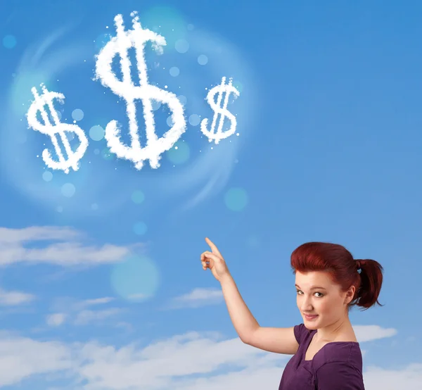 Young girl pointing at dollar sign clouds on blue sky — Stock Photo, Image