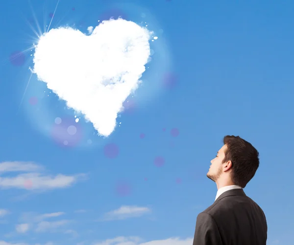 Handsome man looking at white heart cloud on blue sky — Stock Photo, Image