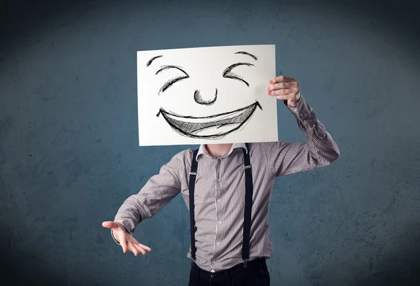 Empresario sosteniendo un papel con la cara sonriente delante de su hea —  Fotos de Stock