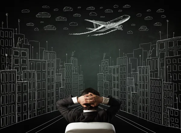 Businessman sitting in front of a cityscape drawing on a chalkbo — Stock Photo, Image