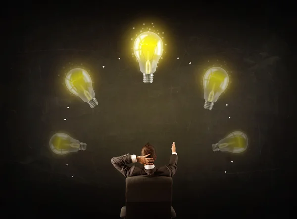 Businessman sitting with lightbulbs over his head — Stock Photo, Image