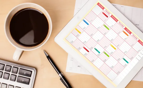 Tablet pc showing calendar on screen with a cup of coffee on a d — Stock Photo, Image