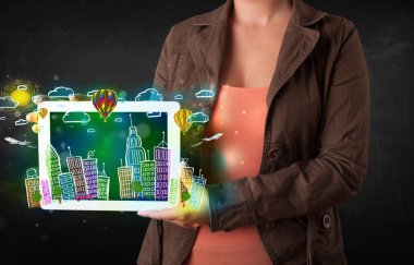 Elle çizilmiş şehir manzaralı tablet gösteren genç kişi