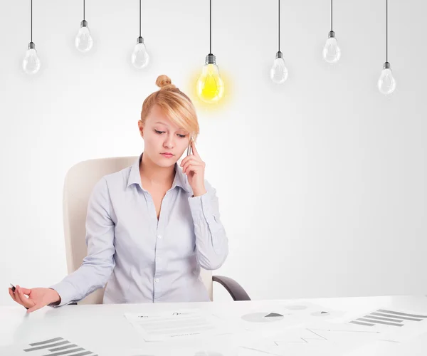 Business woman sitting at table with idea light bulbs Stock Picture