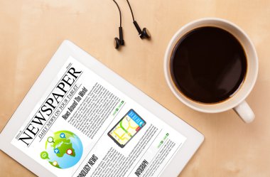 Tablet bilgisayarı haberleri ekranda bir fincan kahveyle sunar.