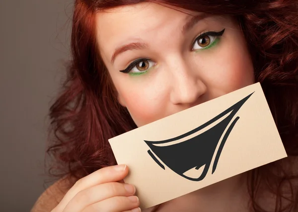 Feliz linda chica sosteniendo papel con divertido dibujo sonriente — Foto de Stock