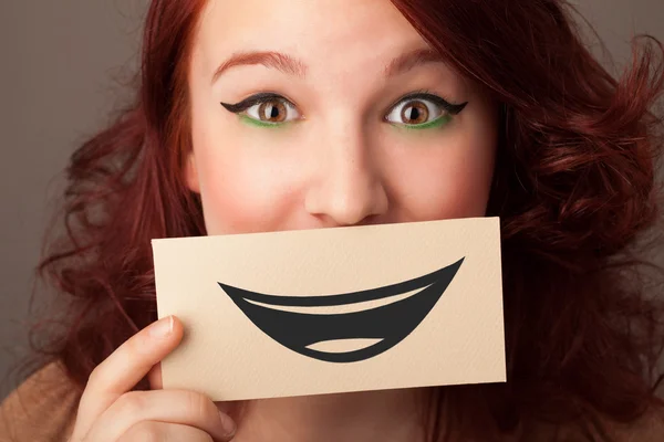 Feliz bonita mujer sosteniendo tarjeta con divertido smiley — Foto de Stock