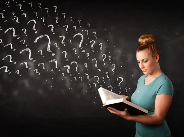 Hübsche Frau liest ein Buch mit Fragezeichen — Stockfoto