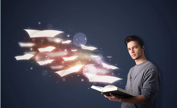 Junger Mann liest ein Buch mit fliegenden Laken, die aus dem — Stockfoto