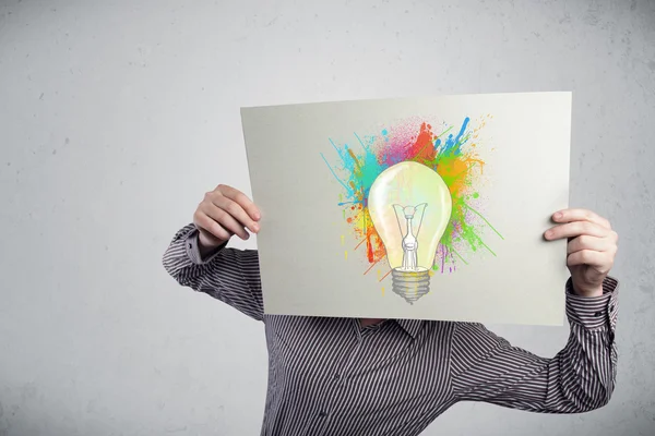 Empresário segurando um papelão com salpicos de tinta e lightbul — Fotografia de Stock