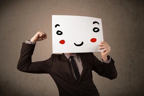 Businessman holding a cardboard with a smiley face on it — Stock Photo, Image