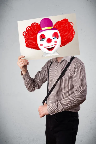 Geschäftsmann hält einen Karton mit einem Clown davor — Stockfoto