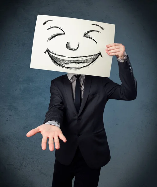 Empresário segurando um papel com rosto sorridente na frente de sua hea — Fotografia de Stock