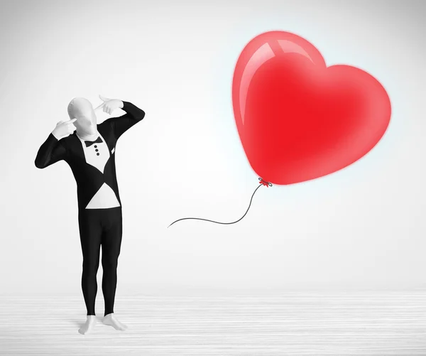 Leuke kerel in morpsuit body suit kijken naar een ballon vormige hart — Stockfoto