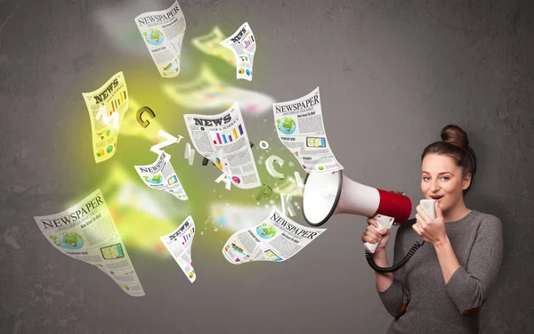 Girl yelling into loudspeaker and newspapers fly out — Stock Photo, Image