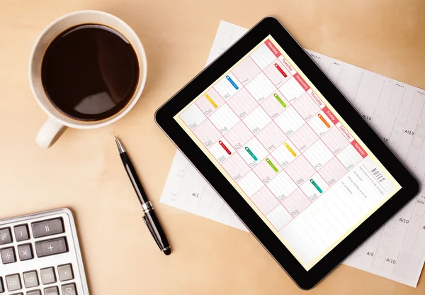 Tablet-PC zeigt Kalender auf dem Bildschirm mit einer Tasse Kaffee auf einem d — Stockfoto