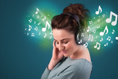 Kulaklıklı genç bir kadın müzik dinliyor.
