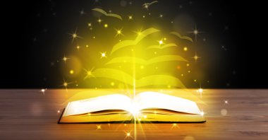 Altından parlak uçan kağıt sayfaları olan açık bir kitap