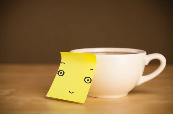 Nota post-it con la cara sonriente pegada en una taza — Foto de Stock