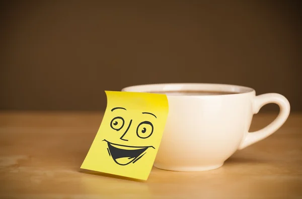 Nota post-it con la cara sonriente pegada en una taza — Foto de Stock