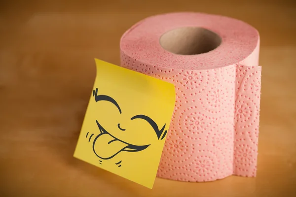 Post-it note with smiley face sticked on a toilet paper — Stock Photo, Image