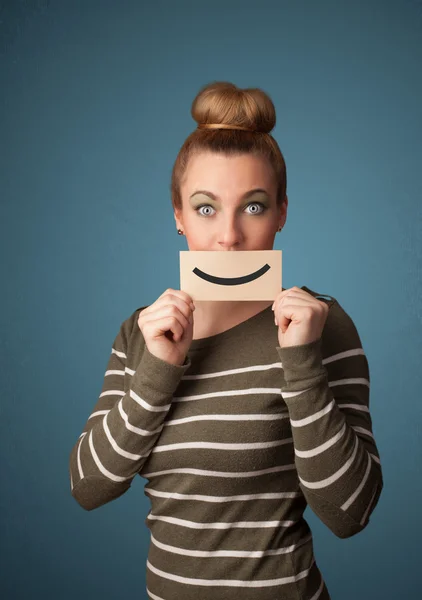 Feliz bonita mujer sosteniendo tarjeta con divertido smiley — Foto de Stock