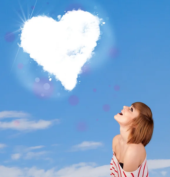 Niedliches Mädchen schaut auf weiße Herzwolken am blauen Himmel — Stockfoto