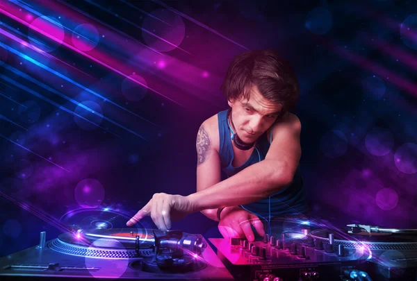 Young DJ playing on turntables with color light effects — Stock Photo, Image