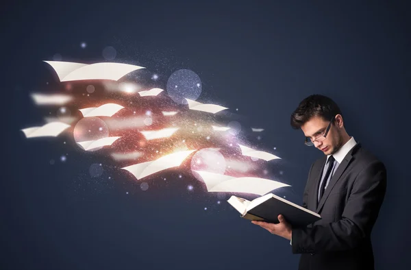 Young guy reading a book with flying sheets coming out of the bo — Stock Photo, Image