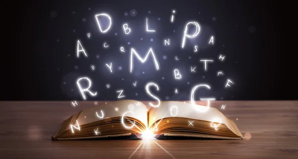 Åpen bok med glødende bokstaver som flyr ut – stockfoto