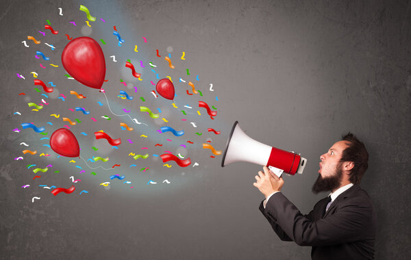 Young guy having fun, shouting into megaphone with balloons 