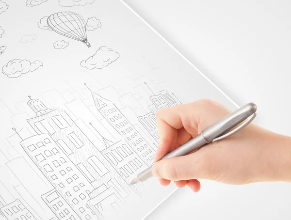 A person drawing sketch of a city with balloons and clouds on a — Stock Photo, Image